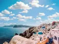 Widok na białe domy z niebieskimi kopułami na Santorini. Zastanawiasz się, ile się leci do Grecji, by podziwiać takie krajobrazy?