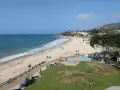 Słoneczny dzień na Laguna Beach. Ludzie spacerują po plaży i drewnianej promenadzie, dzieci bawią się na placu zabaw.