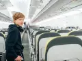 Chłopiec z słuchawkami na szyi w pustym samolocie. Zastanawia się, od ilu lat można latać samemu.