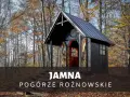 Drewniana kapliczka w lesie, jesienią. Na schodach przed wejściem stoją narty. To urokliwa **Jamna** na Pogórzu Rożnowskim.