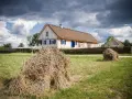 Tradycyjne chaty z krytymi strzechą dachami, jak te w skansenach w Polsce, otoczone plecionymi płotami i stogami siana.