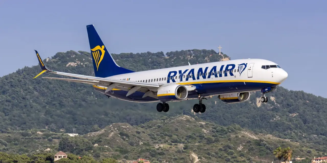 Ryanair ląduje na tle zielonych wzgórz i krzyża na szczycie.