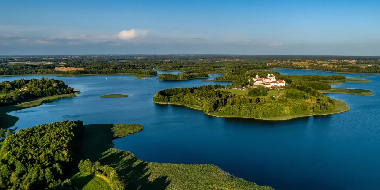 Malowniczy wschód Polski nad jeziorem, z wyspą i klasztorem.