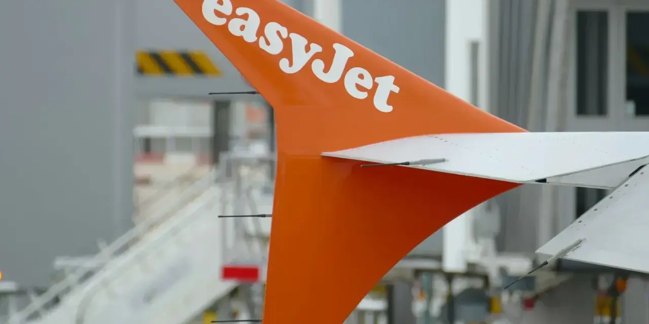 Pomarańczowy statecznik pionowy samolotu easyJet z białym logo, gotowy do przyjęcia bagażu pasażerów.