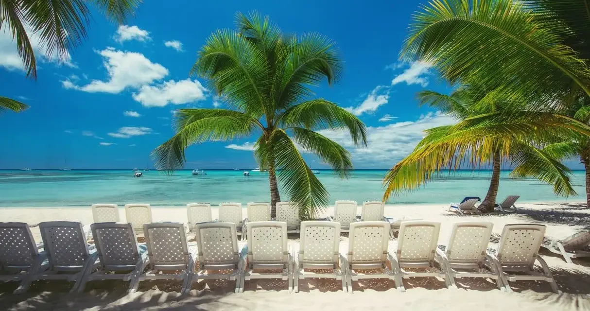 Rajska plaża z palmami i leżakami. Zastanawiasz się, ile się leci na Dominikanę? To idealne miejsce na relaks!