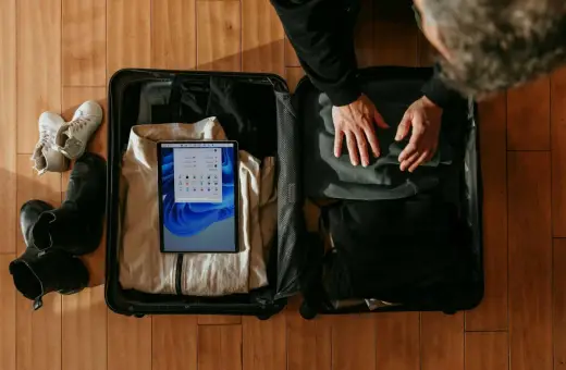 Pakowanie lot bagaż: tablet z systemem Windows, ubrania, buty i akcesoria.