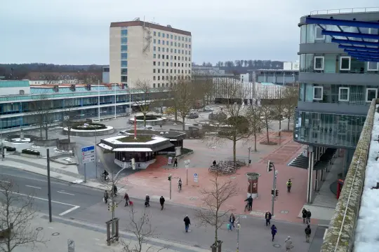 Widok na plac miejski w Wolfsburg. Miasto tętni życiem, ludzie spacerują, jeżdżą na rowerach.