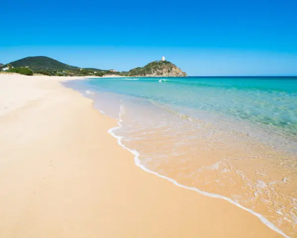Piękne plaże Cagliari z turkusową wodą i piaszczystym brzegiem, na wzgórzu majaczy biała wieża.