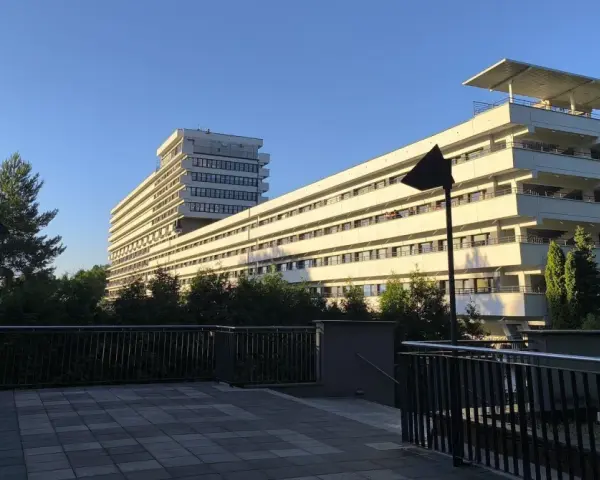 Nowoczesny budynek z tarasami, otoczony zielenią, idealny dla szukających najlepszych sanatoriów w Polsce.