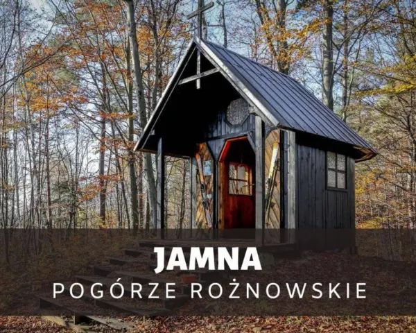 Drewniana kapliczka w lesie, jesienią. Na schodach przed wejściem stoją narty. To urokliwa **Jamna** na Pogórzu Rożnowskim.