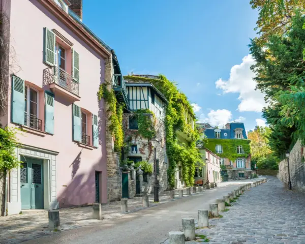 Urokliwa, brukowana uliczka w paryskiej dzielnicy le Marais, z pastelowymi kamienicami porośniętymi bluszczem.