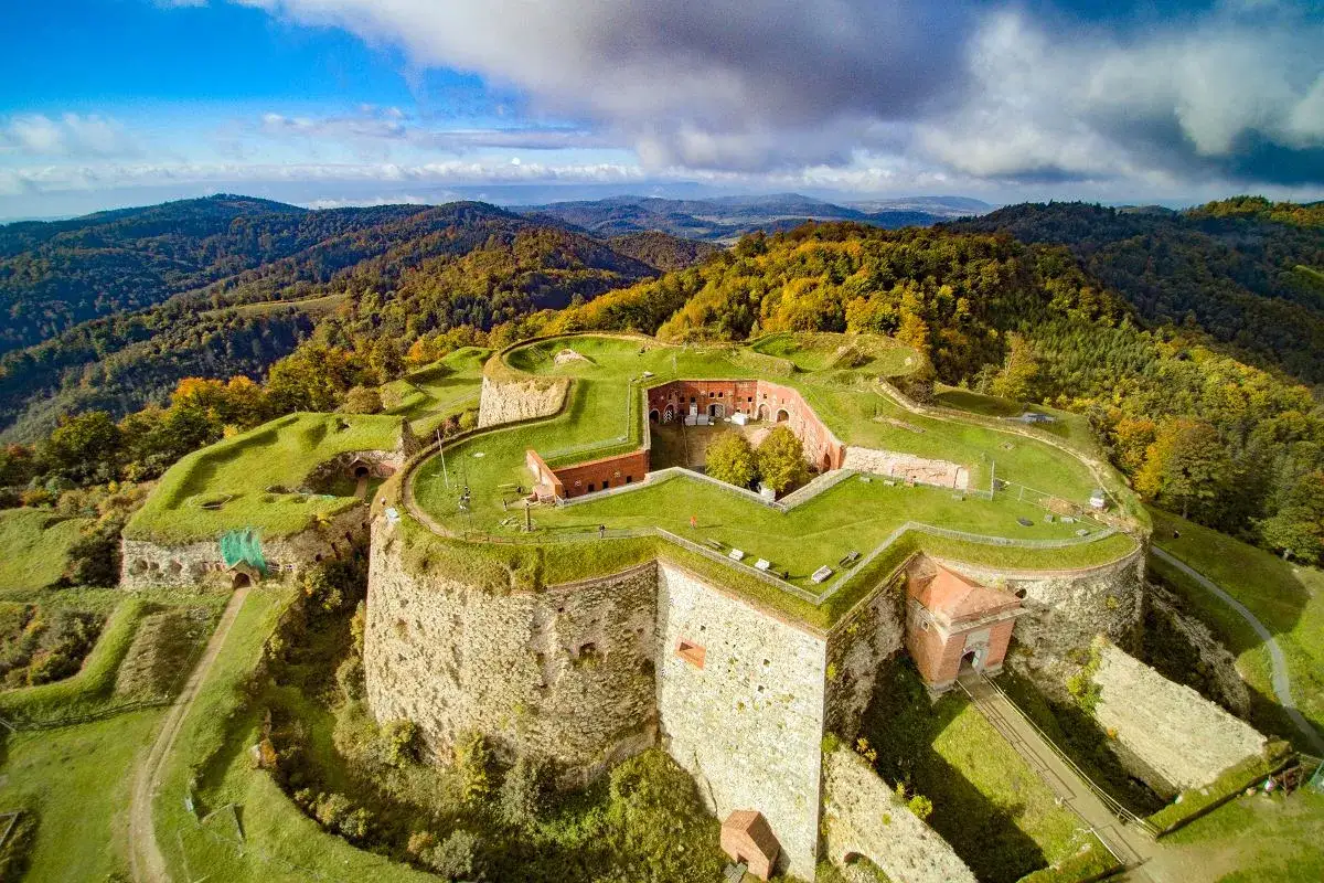 Twierdza w górach, zieleń i jesienne barwy lasów. To wschód Polski, gdzie historia spotyka się z naturą.